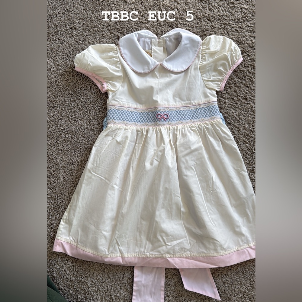 The Beaufort Bonnet Company Ivory Dress with Bow Pink Trim and Blue Smocking